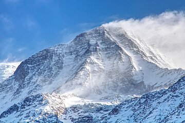 A snowy mountain with a blue sky in the background