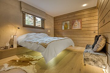 A cozy, modern bedroom with warm wood walls & floor, a 