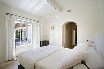 A white bedroom with a bed and a window