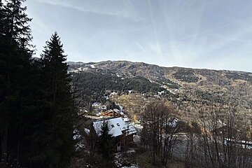 A house in the middle of a snowy mountain surrounded by trees