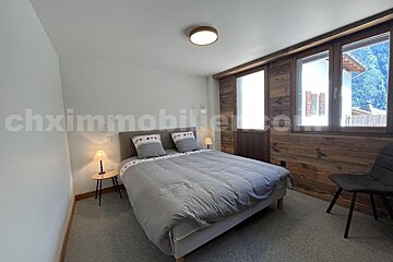 A bedroom with a bed and a chair and the website chximmobilier.com