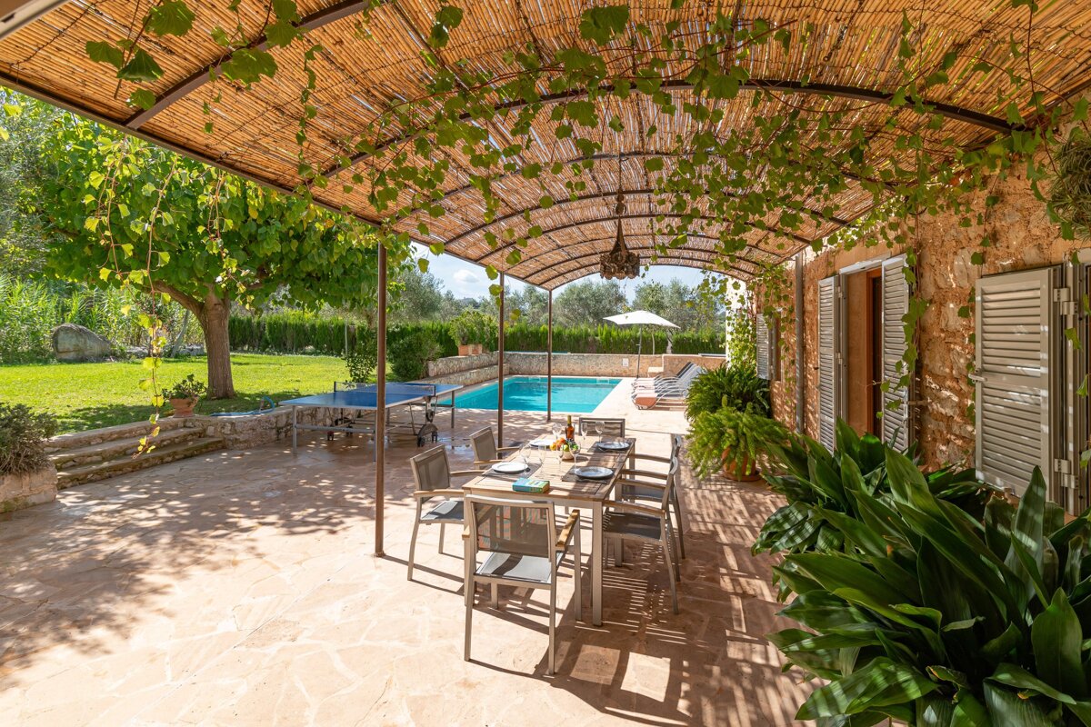 A patio with a table and chairs under a thatched roof