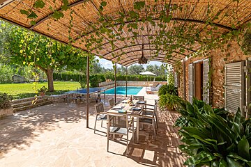 A patio with a table and chairs under a thatched roof