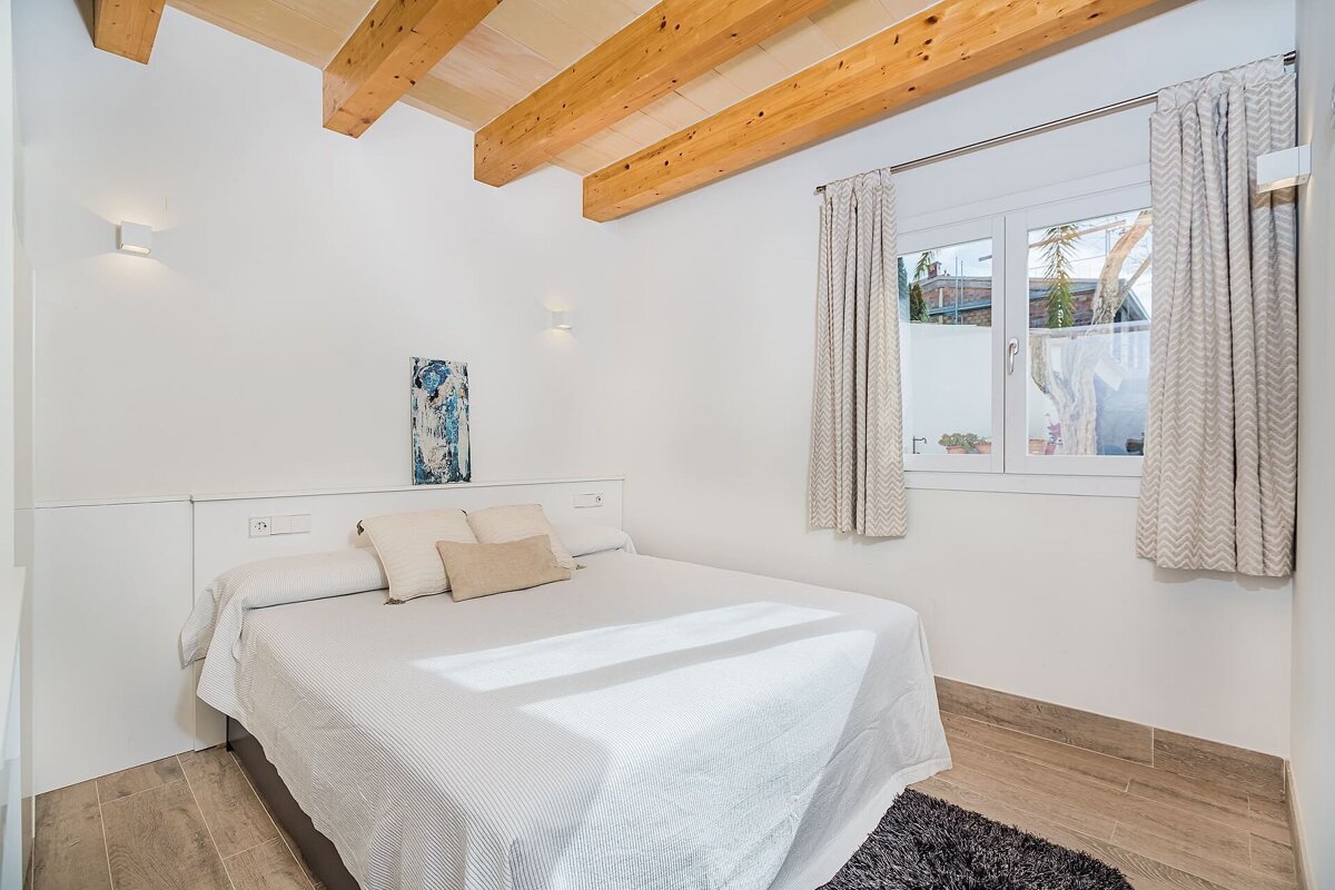 A bedroom with a bed and a window with wooden beams