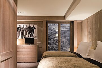 A bedroom with two beds and a painting on the wall