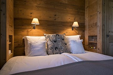 A bed with pillows and a wooden wall behind it