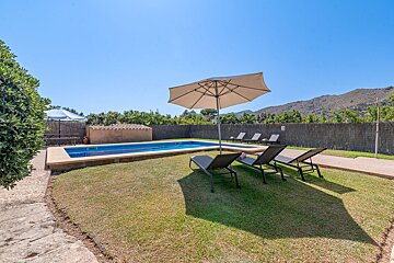A swimming pool surrounded by lawn chairs and an umbrella