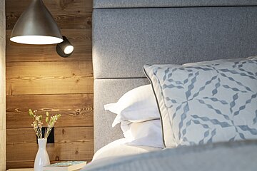 A bed with pillows and a lamp next to it