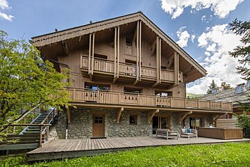 A large wooden house with a stone wall and stairs