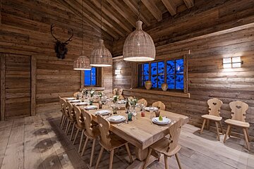 A wooden dining room with a long table and chairs