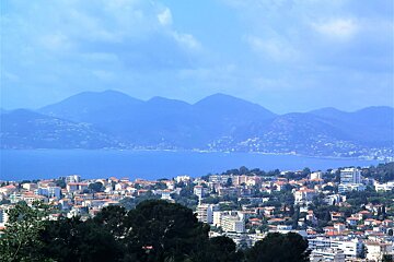A city with mountains in the background and a body of water in the foreground