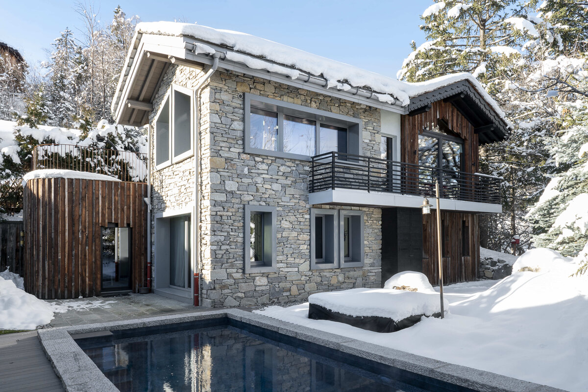 A snowy house with a swimming pool in front of it