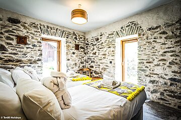 A bedroom with a stone wall and two beds