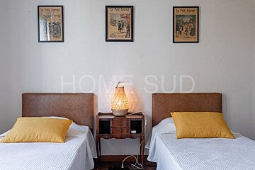 A bedroom with two beds and three framed newspapers on the wall with home sud written on the bottom