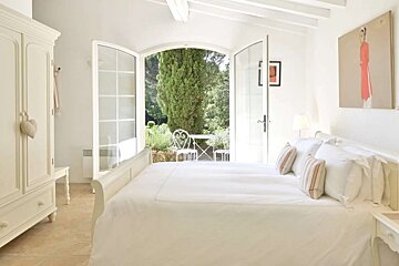 A bedroom with a large bed and a painting on the wall