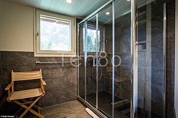 A bathroom with a sliding glass shower door and a chair