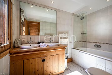 A bathroom with two sinks and a bathtub with the word tenda on the wall