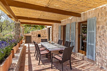 A patio with a table and chairs under a thatched roof