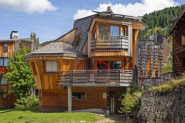 A wooden house with a balcony has a sign on it that says 