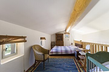 A bedroom with a bed a chair and a crib