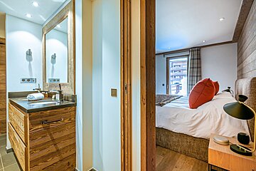 A bathroom with a sink and a mirror next to a bedroom