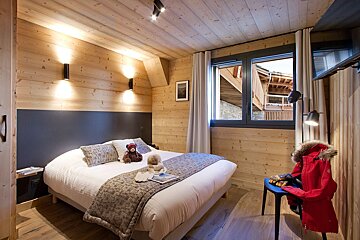 A bedroom with a bed and a teddy bear on it