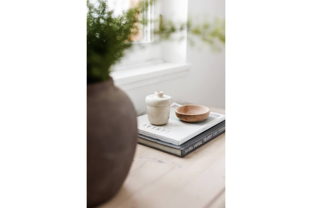 A book called cereal sits on a table next to a vase