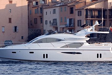 A white yacht is floating in the water near buildings