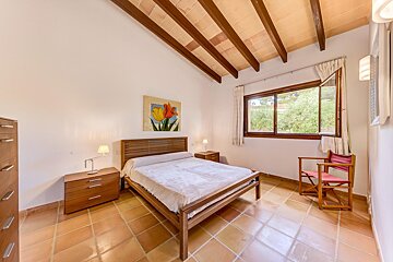 A bedroom with a painting of flowers on the wall above the bed