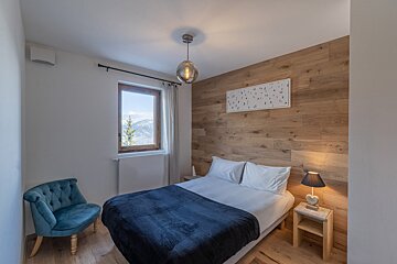A bedroom with a bed a chair and a lamp