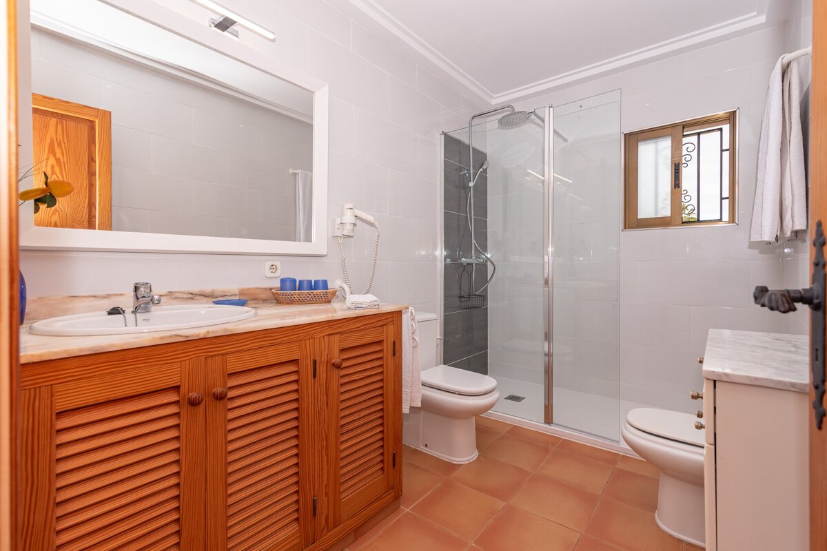 A bathroom with two toilets and a walk in shower