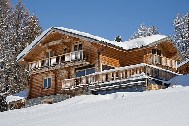 A large wooden house is covered in snow