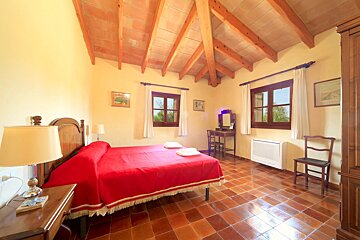 A bedroom with a wooden ceiling and a red bed