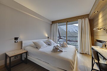 A hotel room with a large bed and a desk