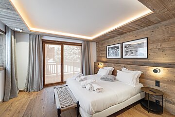 A bedroom with a large bed and a sliding glass door
