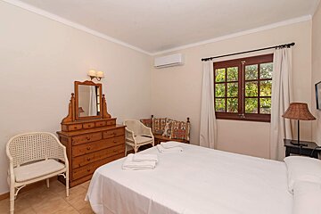 A bedroom with a bed dresser and chairs