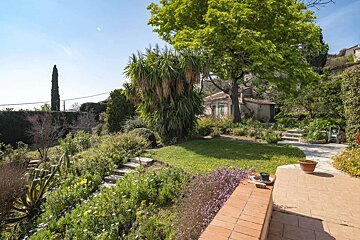 A lush green garden with a house in the background