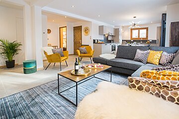 A living room with a gray couch and yellow chairs