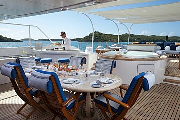 A man stands behind a table set for a meal on a boat