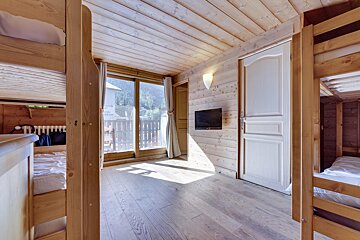 A bedroom with bunk beds and a flat screen tv on the wall