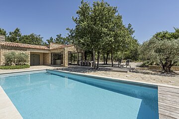 A large swimming pool in front of a stone house