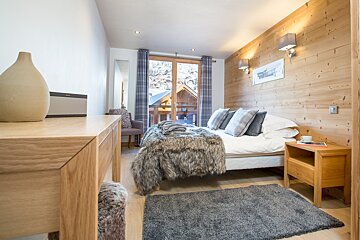 A bedroom with wood paneling and a bed with a fur blanket