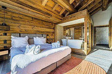 A bedroom with a large bed and a bathtub