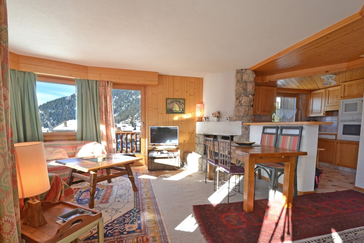 A living room with a table and chairs and a television