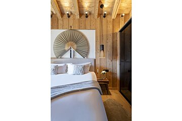 A bedroom with a fan on the wall above the bed