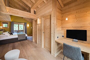 A bedroom with a bed and a desk with a computer on it