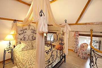 A bedroom with a canopy bed and a chair