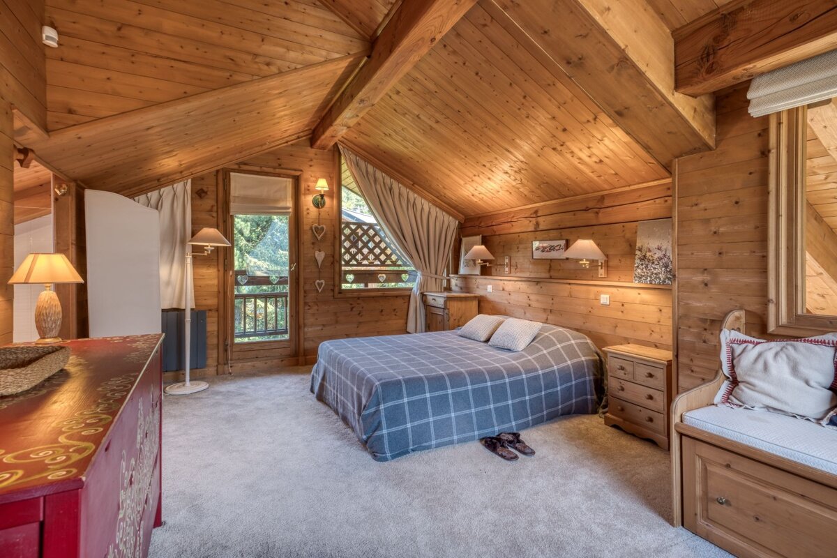 A bedroom in a log cabin with a bed and dresser