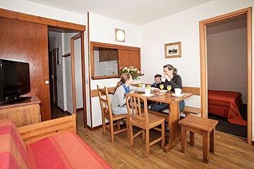 A woman sitting at a table with a child drinking orange juice