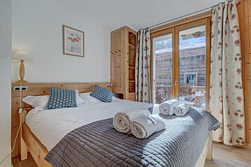 A bedroom with a large bed and a picture on the wall